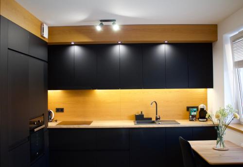 a kitchen with black cabinets and a sink at K&M Apartament Panorama in Bochnia