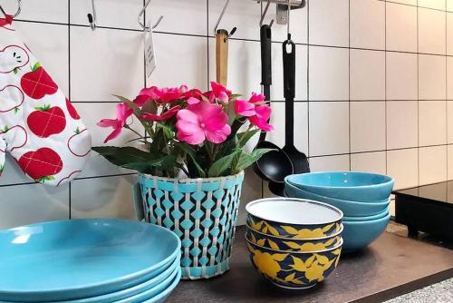 a vase with pink flowers sitting on a counter with bowls at Pannarai's House in Bangkok