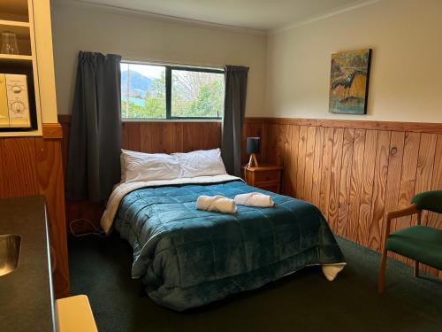 1 dormitorio con 1 cama con 2 toallas en Kiwi Park Motels, en Murchison