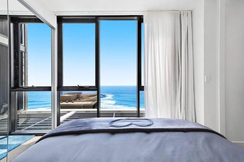 a bedroom with a bed with a view of the ocean at Exceptional Beach views - Luxury apartment in Newcastle
