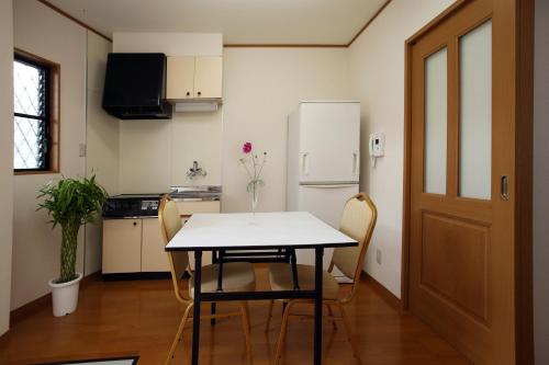 a kitchen with a table and chairs and a refrigerator at Shikinosato Yuraku in Shirahama