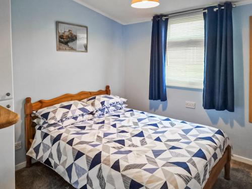 a bedroom with a bed with a blue and white comforter at Seabreeze in Llangain