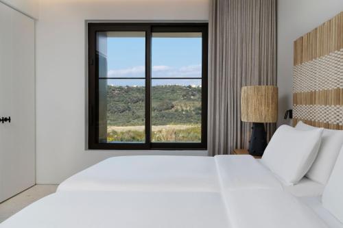 a bedroom with a large white bed and a window at W Costa Navarino in Pylos