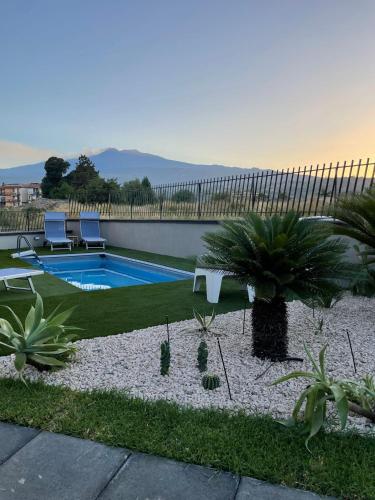 un patio trasero con piscina y palmeras en Trinacria dell'Etna en Fiumefreddo di Sicilia