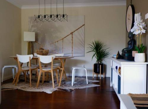 uma sala de jantar com uma mesa e cadeiras brancas em Sunny 2 bed Restaurants beach at door Pets O.K em Sydney