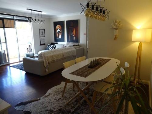 a living room with a bed and a table and a couch at Sunny 2 bed Restaurants beach at door Pets O.K in Sydney