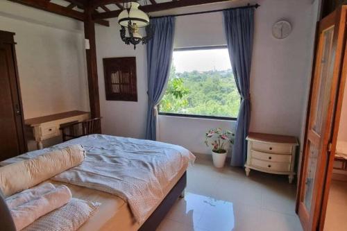 ein Schlafzimmer mit einem Bett und einem großen Fenster in der Unterkunft Villa Sajodo [Hilltop Get Away w/ Valley View] in Bandung