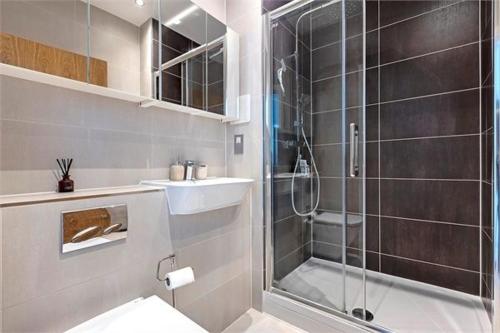 a bathroom with a shower and a toilet and a sink at The Harbour- Stylish spacious family sized apartment in London
