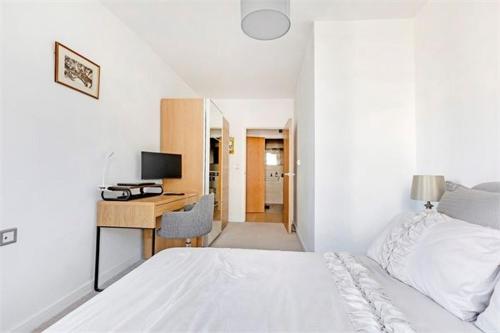 a bedroom with a bed and a desk with a computer at The Harbour- Stylish spacious family sized apartment in London