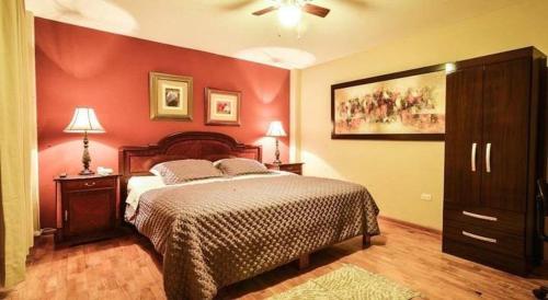 een slaapkamer met een bed en een rode muur bij Hotel Las Condes in Trujillo