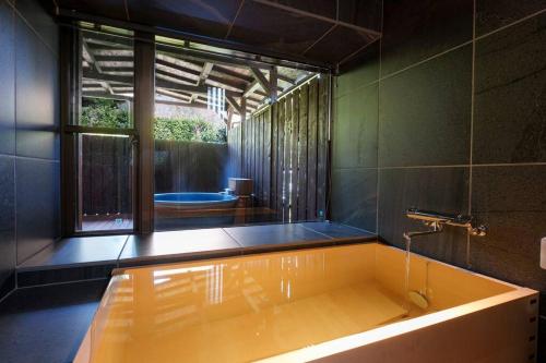 a bath tub in a bathroom with a window at じぇーむすのおうち in Yawatano