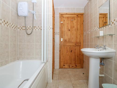 a bathroom with a tub and a sink and a shower at Ty Hen in Pwllheli