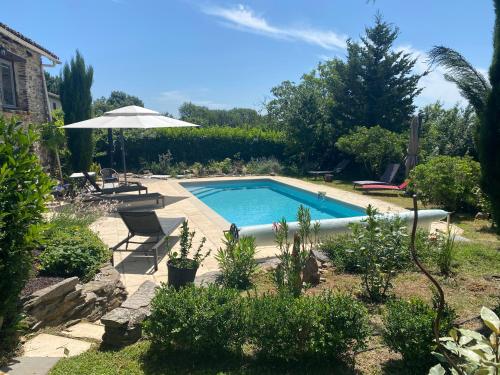 une piscine dans une cour avec un parasol dans l'établissement Maison d'Hôtes Hameau de Taur, à Villefranche-dʼAlbigeois