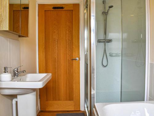 W łazience znajduje się umywalka i prysznic. w obiekcie Swift Cottage w mieście Chilton Polden 