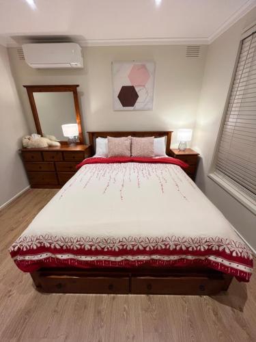 a bedroom with a large bed with a red blanket at Cosy 3 bedroom family home near beach and shops in Frankston