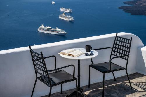 a table and chairs on a balcony with a view of the water at Eteoro Suites in Imerovigli