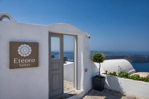 a sign on the side of a white building with a door at Eteoro Suites in Imerovigli