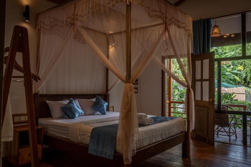 暹粒的住宿－Habana Angkor Boutique Hotel，一间卧室配有带窗帘的天蓬床