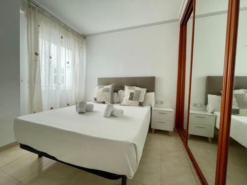 a bedroom with a large white bed and a mirror at Apartamento Alderetes in Córdoba