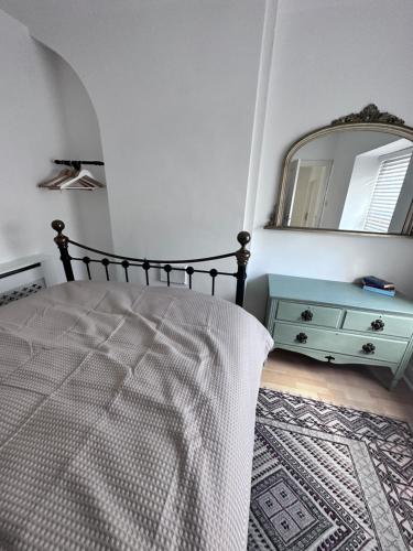 a bedroom with a bed with a dresser and a mirror at Coetmor Cottage in Llanfairfechan