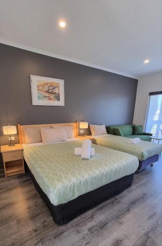 two beds in a room with two tables and lamps at Seaview Motel & Apartments in Apollo Bay