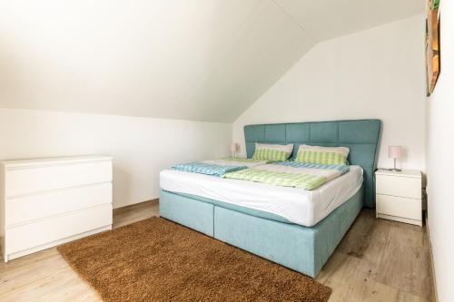 um quarto com uma cama azul e duas mesas de cabeceira em Ferienwohnung Grüner Weg mit Grillplatz em Tecklenburg