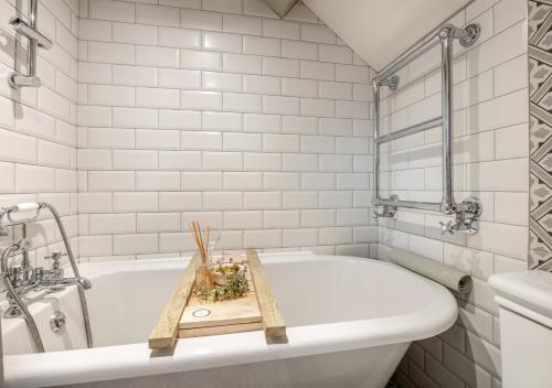 ein Badezimmer mit einer weißen Badewanne und einem Holztablett darauf in der Unterkunft 2 Browcote Cottage in Ravenscar