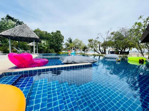 a swimming pool with two pink chairs in the water at Sabaii Bay Resort in Baan Tai