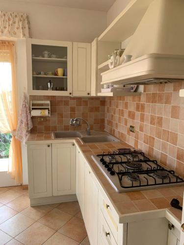 a kitchen with white cabinets and a stove top oven at Casa Viola vicino al mare by SMART-HOME in Vallecrosia
