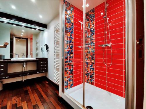 a bathroom with a shower with red tile on the wall at « La Canopée » / La Baule view in La Baule