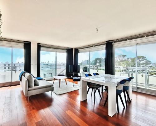 un salon avec une table, des chaises et des fenêtres dans l'établissement « La Canopée » / La Baule view, à La Baule