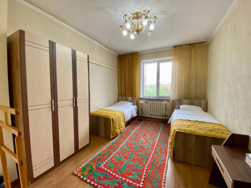 a bedroom with two beds and a rug at Guest House Botanika in Bishkek
