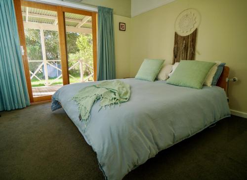 1 dormitorio con 1 cama grande y ventana en Booroolgunyah Luxury Farm Stay, en Booroolite
