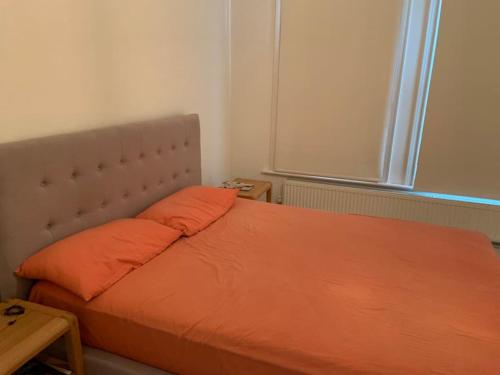 a bed with orange pillows in a small room at London SW Home in London