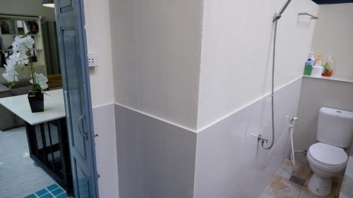 a bathroom with a toilet and a glass shower door at Casa Ari - Trang City Center in Trang