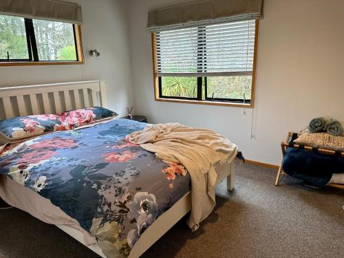 a bedroom with a bed with a blanket on it at Peaceful cottage in beautiful landscaped native bush gully in Tamahere