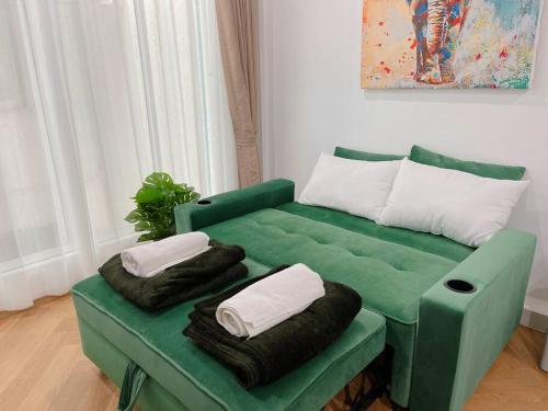 a green couch with two pillows on it in a room at Entire floor,Decorated cozy home, near Grand Palace in Bangkok