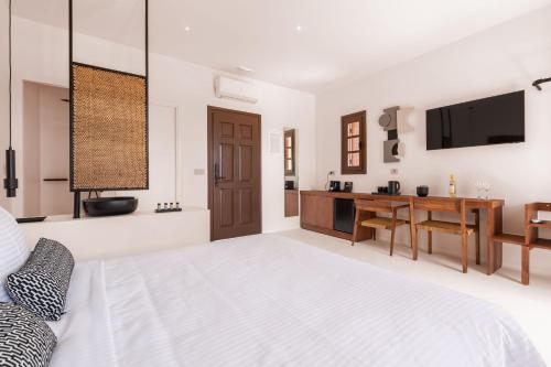 a white bedroom with a bed and a desk at Akre Hotel in Naxos Chora