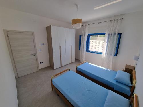a small bedroom with two beds and a window at Villetta Azzurra in Torre Lapillo