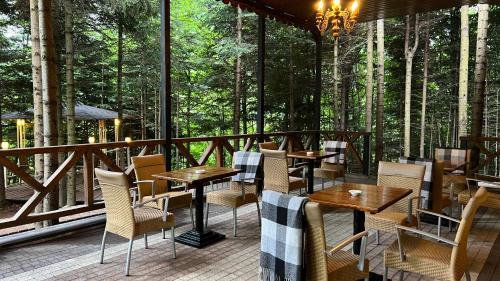 a patio with tables and chairs on a deck with trees at Idylia Grand Villas in Migovo