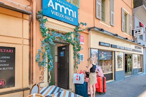 Aparthotel AMMI Vieux Nice في نيس: امرأة تقف أمام متجر مع الأمتعة