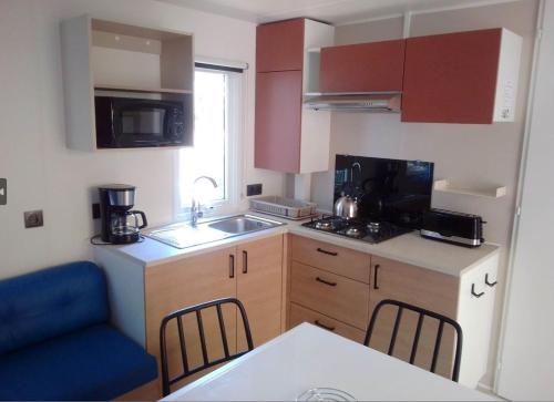 a small kitchen with a sink and a counter at Mobil home Neuf 6 places Climatisé in Camiers