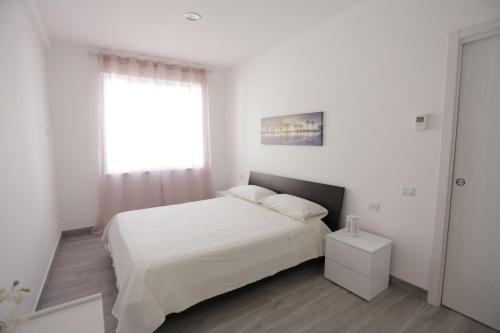 a white bedroom with a white bed and a window at La Suite del Borgo in Bovalino Marina