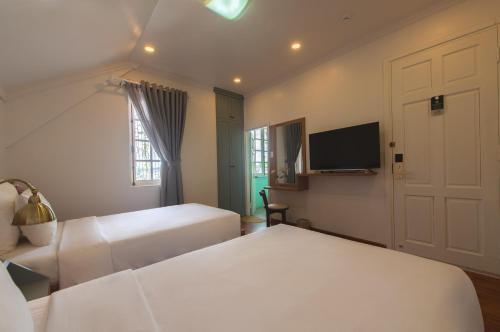 a bedroom with two beds and a flat screen tv at Le Soleil Boutique Hotel in Da Lat