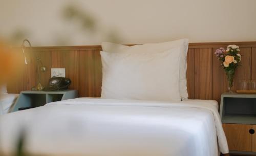 a bed with a white pillow and a vase of flowers at Le Soleil Boutique Hotel in Da Lat