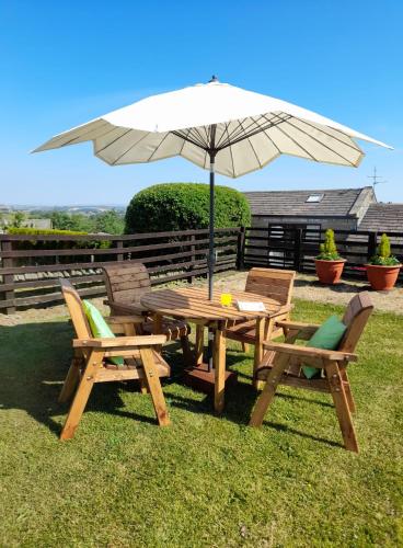 a wooden table and chairs with an umbrella at south view farm cottage 1 Bed in Bradford