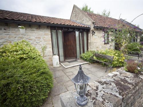 una casa con un porche con una linterna de cristal delante de ella en Beeches Farmhouse Country Cottages & Rooms, en Bradford on Avon