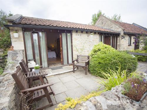 a house with two wooden benches in front of it at Beeches Farmhouse Country Cottages & Rooms in Bradford on Avon