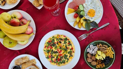 une table rouge recouverte d'assiettes de petit-déjeuner dans l'établissement Silk Road Kokand Hotel, à Kokand