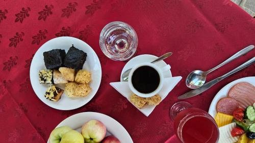- une table rouge avec des assiettes de nourriture et une tasse de café dans l'établissement Silk Road Kokand Hotel, à Kokand